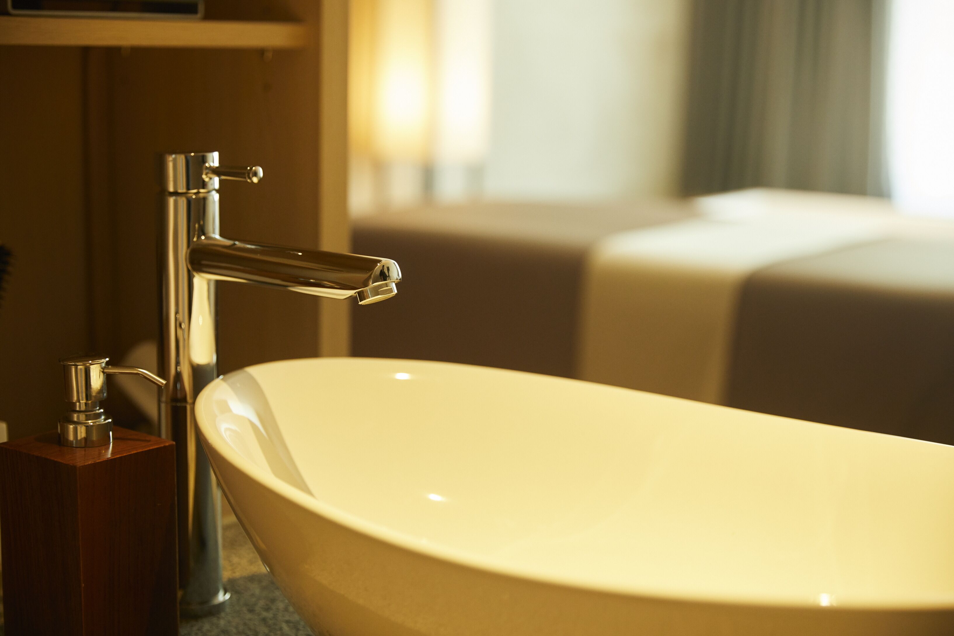 A modern bathroom with a freestanding bathtub, a chrome faucet, and a wooden soap dispenser.