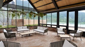 A spacious patio with wicker furniture, large windows, and hanging plants.