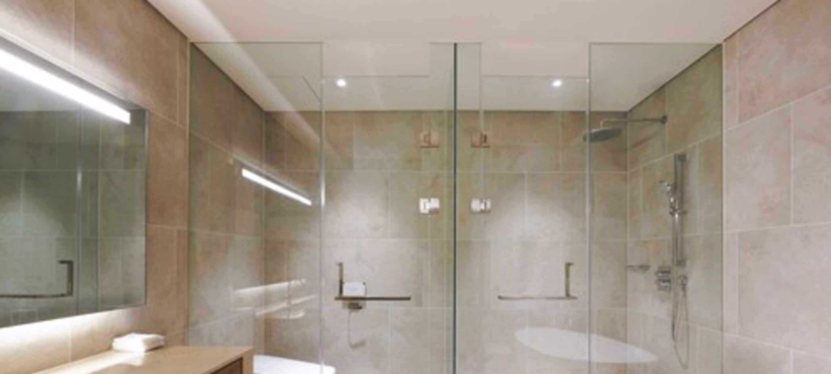 A modern bathroom with a glass shower enclosure, a large mirror, and a wooden vanity.