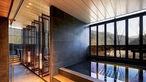 A modern interior with a stone staircase, a glass railing, and a view of the outdoors.