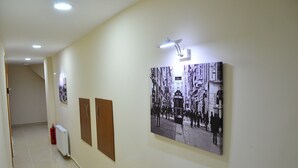 Un pasillo con una fotografía grande en blanco y negro de una escena callejera, un extintor y un radiador.