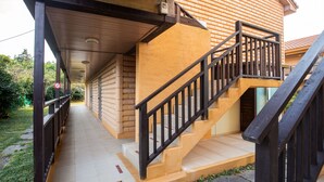 A wooden staircase with a black railing leading to a covered porch. - Red Clay (Jeju City)