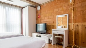 A hotel room with a bed, a TV, a desk, a mirror, and a wooden wardrobe. - Red Clay (Jeju City)