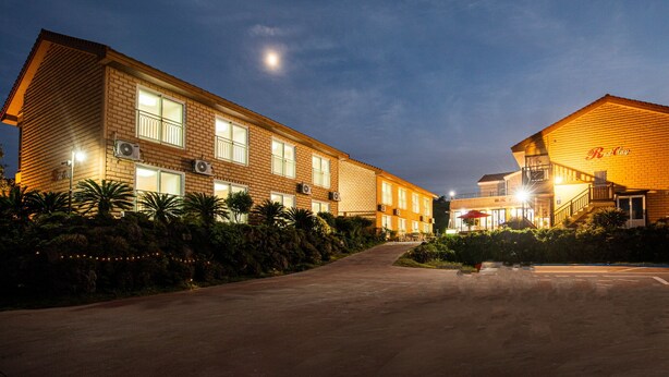 A two-story building with a brick facade, multiple windows, and air conditioning units. - Red Clay (Jeju City)
