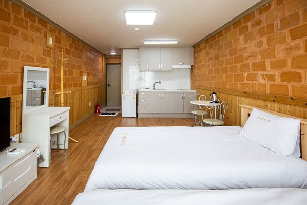 Una habitación de hotel con cama, escritorio con espejo, kitchenette pequeño y pared de madera.