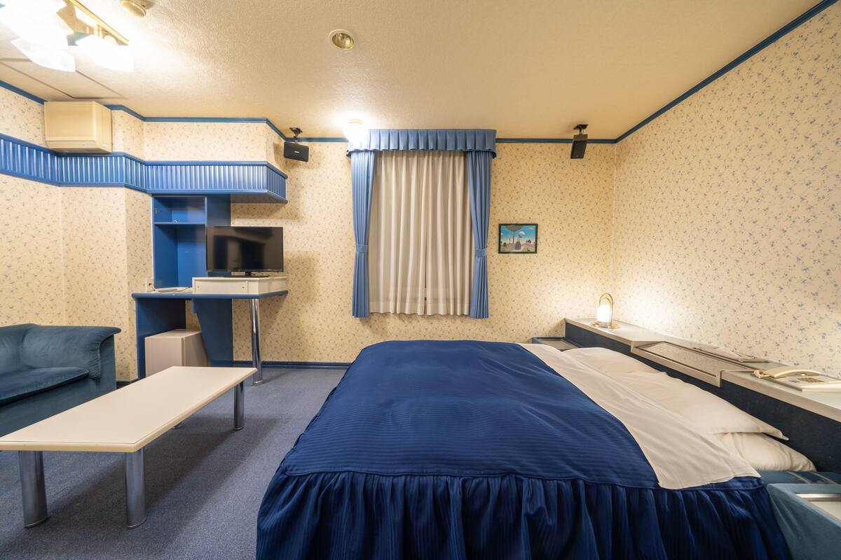 Ein Hotelzimmer mit einem Bett, einem Schreibtisch, einem Stuhl und einem kleinen Tisch.