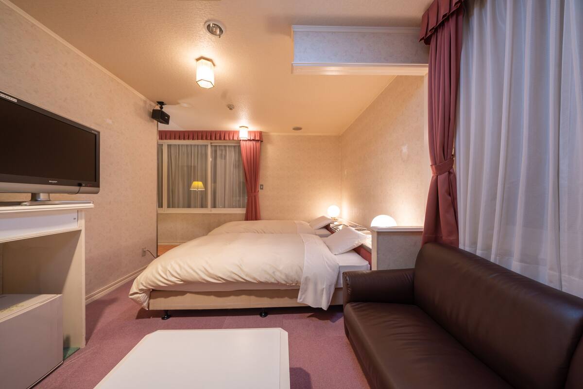 Ein Hotelzimmer mit Bett, einer Couch, einem Fernseher und einem Schreibtisch.