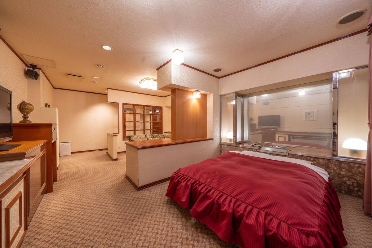 Ein Hotelzimmer mit einem großen Bett, einem Schreibtisch mit Globus, einem Spiegel und Blick auf die Stadt durch das Fenster.