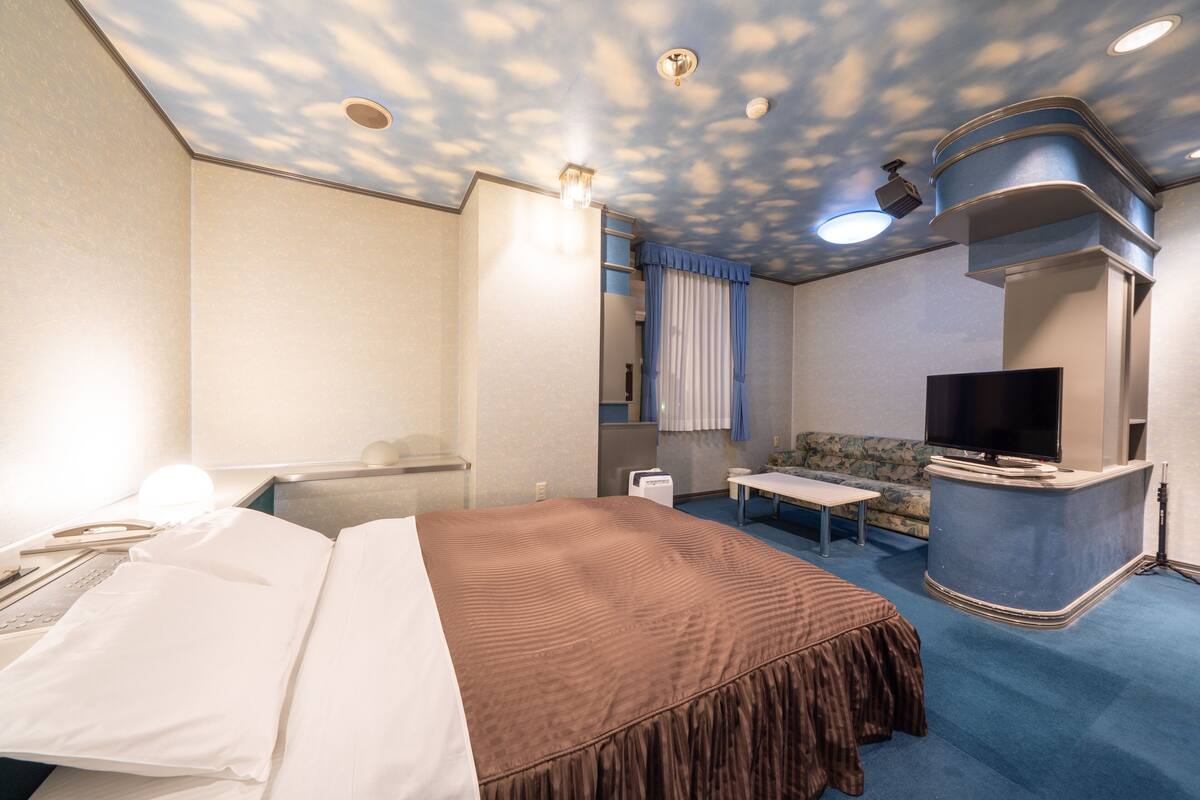 Ein Hotelzimmer mit Bett, Schreibtisch, Fernseher und Sofa.