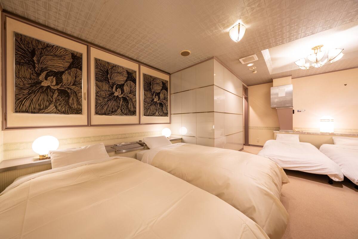Ein Hotelzimmer mit zwei Betten, einem großen Spiegel und Bildern an der Wand.