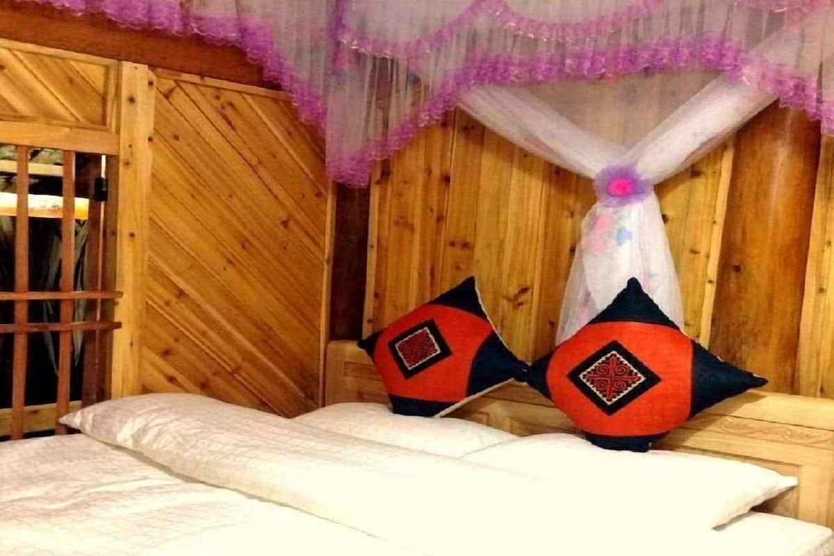 A wooden room with a bed, a window with bars, and a mosquito net.