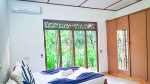 A bedroom with a bed, a window with decorative metal bars, a wardrobe, and an air conditioning unit. - Sigiri Thilanka Rest (Sigiriya)
