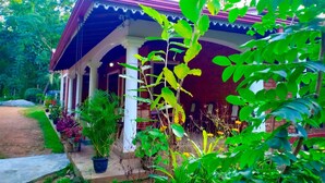 A covered outdoor area with a red roof, white columns, and potted plants. - Sigiri Thilanka Rest (Sigiriya)