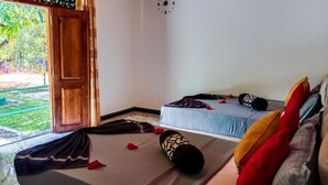 A room with a bed, a sofa, and a wooden door leading outside. - Sigiri Thilanka Rest (Sigiriya)