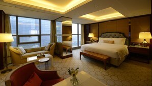 Una habitación de hotel con una cama grande, un sofá, una mesita y un espejo.