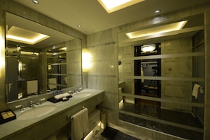 A modern bathroom with two sinks, a large mirror, and a shower area.