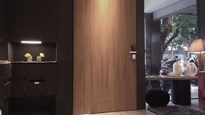 A modern room with a wooden door, a desk with a lamp, and a view of the street outside. - Chez Taipei No5 (Taipei)
