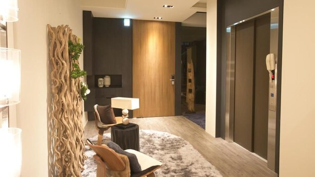 A modern hotel lobby with a wooden accent wall, a seating area with a table and chairs, and an elevator. - Chez Taipei No5 (Taipei)