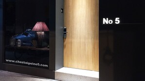 A modern building facade with a large window displaying a lamp and a car. The address "No 5" is visible on the right side. - Chez Taipei No5 (Taipei)