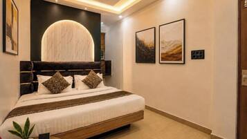 Une chambre moderne avec un lit, un ventilateur de plafond, un luminaire fixé au mur et des œuvres d’art encadrées.