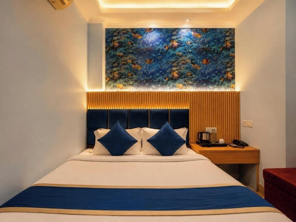A hotel room with a bed, a nightstand, a red chair, and a wall mural.