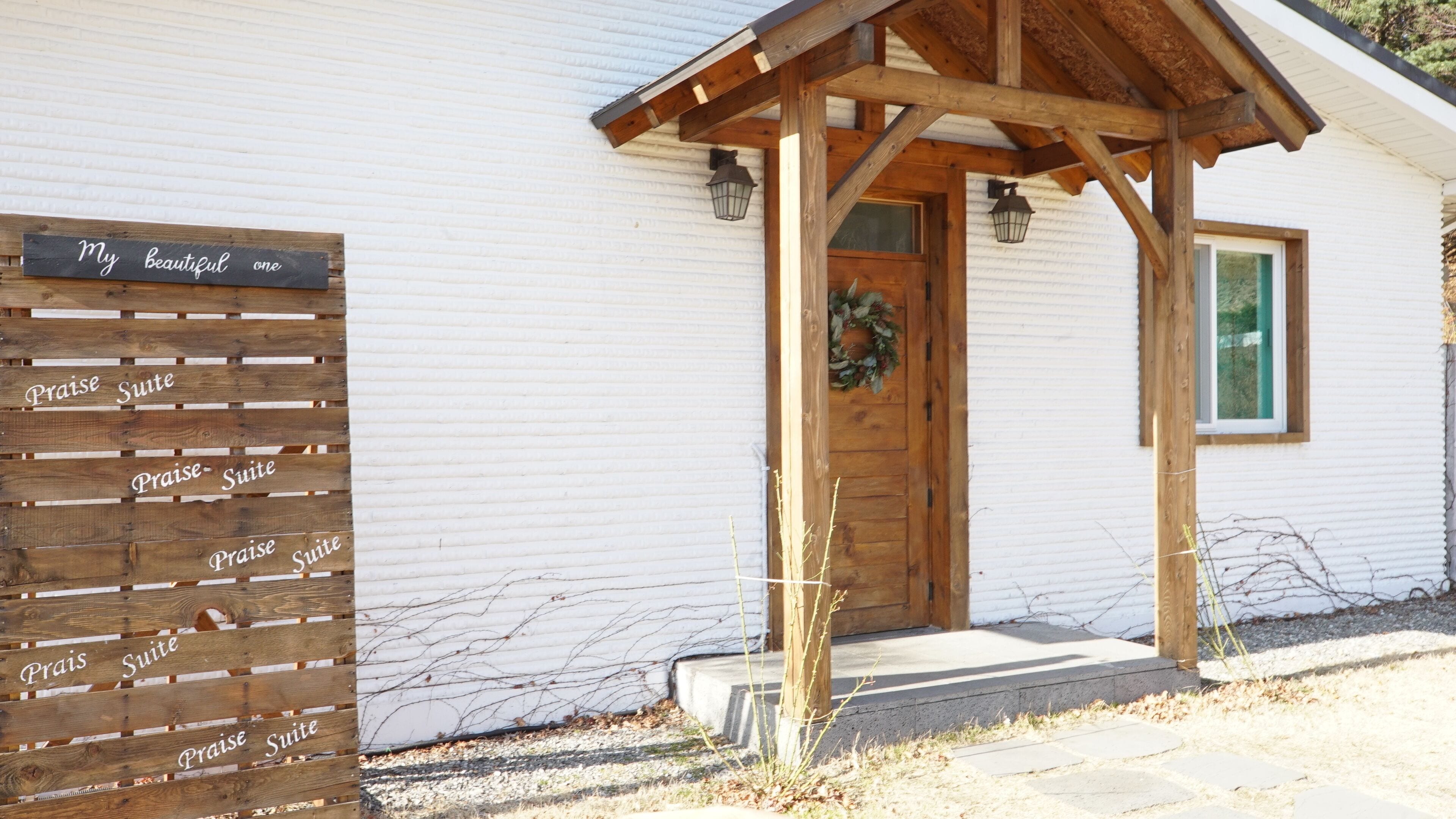 A white building with a wooden entrance and a sign reading "My beautiful one."