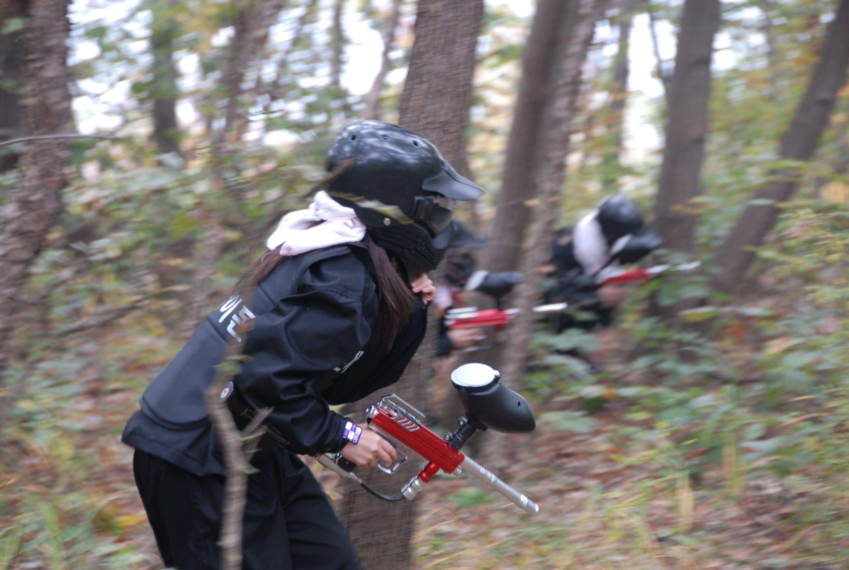 A person in a forest holding a paintball gun.