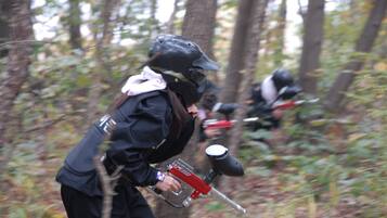 A person in a forest holding a paintball gun.