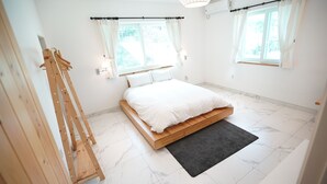 A bedroom with a wooden bed, two windows with curtains, a wall-mounted lamp, and a wooden ladder.