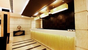 A modern reception area with a marble floor, a reception desk, and a wall-mounted TV. - Cenneys Gateway - Pride of Salem (Salem)