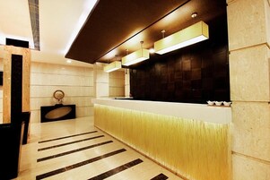 Una moderna zona de recepción con suelo de mármol, un mostrador de recepción y un televisor de pared.