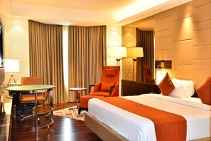 Una habitación de hotel con cama, escritorio, silla, lámpara y espejo.