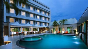A modern hotel with a swimming pool, outdoor seating, and a well-lit facade. - Cenneys Gateway - Pride of Salem (Salem)