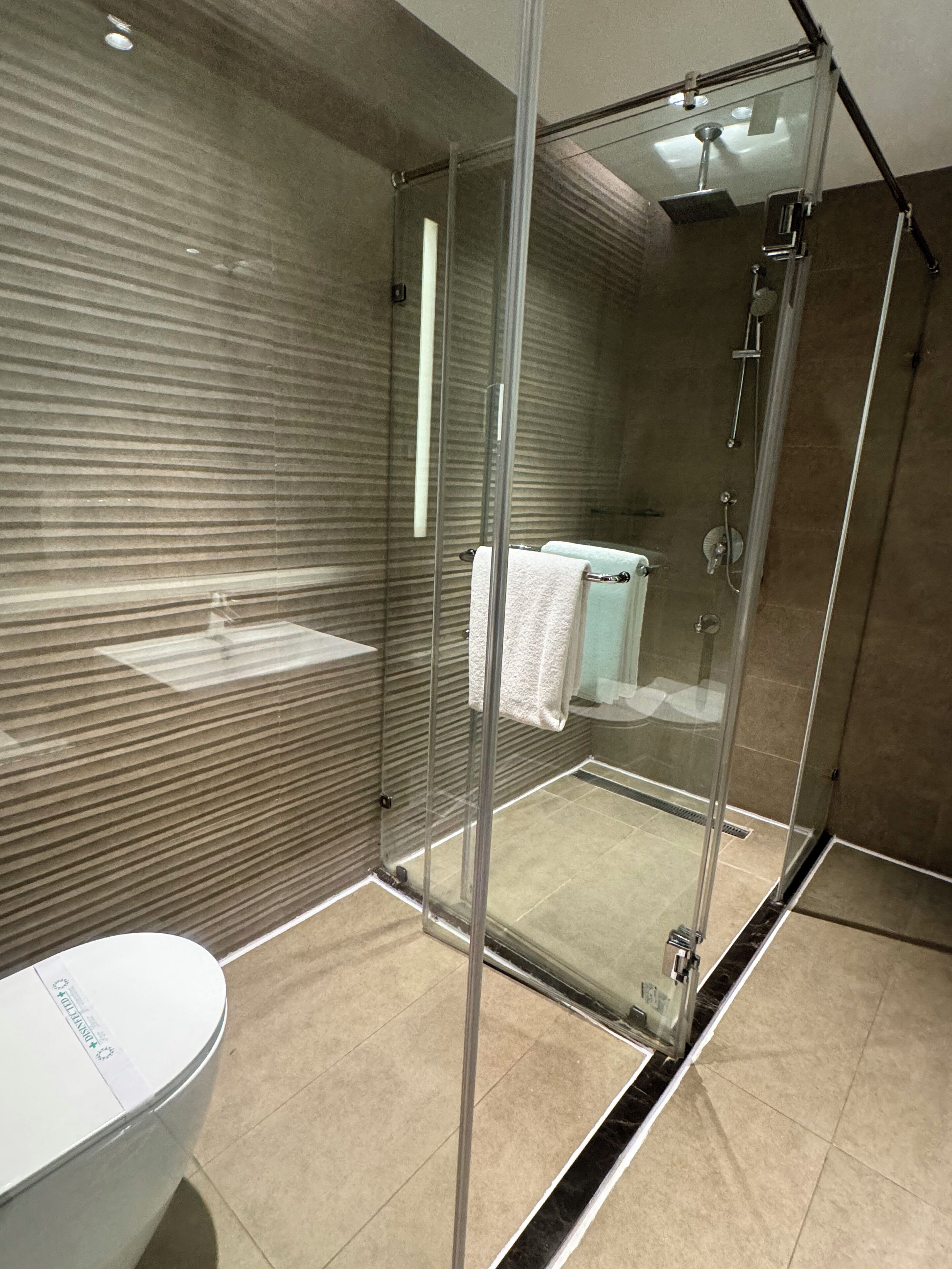 Une salle de bain moderne avec une douche à parois de verre, un lavabo blanc et un porte-serviettes.