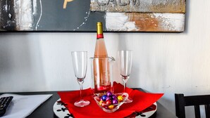 A table with a bottle of champagne, two glasses, and a bowl of colorful chocolates on a red napkin. - A Casa di Enza (Rome)