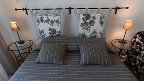 A bed with striped bedding, two pillows with floral patterns, and two bedside lamps. - A Casa di Enza (Rome)