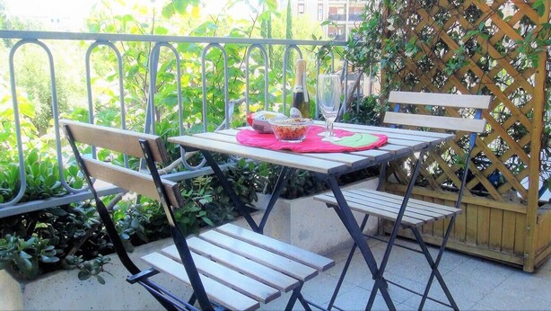 A patio with a table set for two, a bottle of champagne, and a bowl of snacks. - A Casa di Enza (Rome)