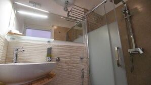 A modern bathroom with a large sink, a glass shower enclosure, and a towel rack. - A Casa di Enza (Rome)