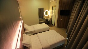 A hotel room with two beds, a mirror with a light, a television, and a door. - Pantai Regal Hotel (Kuantan)