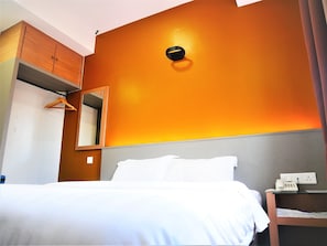 A hotel room with a bed, a bedside table with a phone, a mirror, and a wardrobe. - Pantai Regal Hotel (Kuantan)