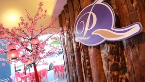 A restaurant with cherry blossom decorations and a wooden wall with a purple sign. - Pantai Regal Hotel (Kuantan)