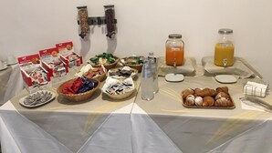 A breakfast buffet with various food items, including pastries, biscuits, and juice dispensers. - Moonlight Hotel & Suites (Catania)