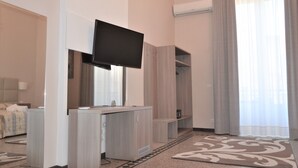A hotel room with a bed, a TV mounted on the wall, a wardrobe, and a window with curtains. - Moonlight Hotel & Suites (Catania)