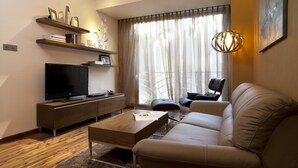 Un salon moderne avec un canapé, une table basse, un téléviseur et des étagères.