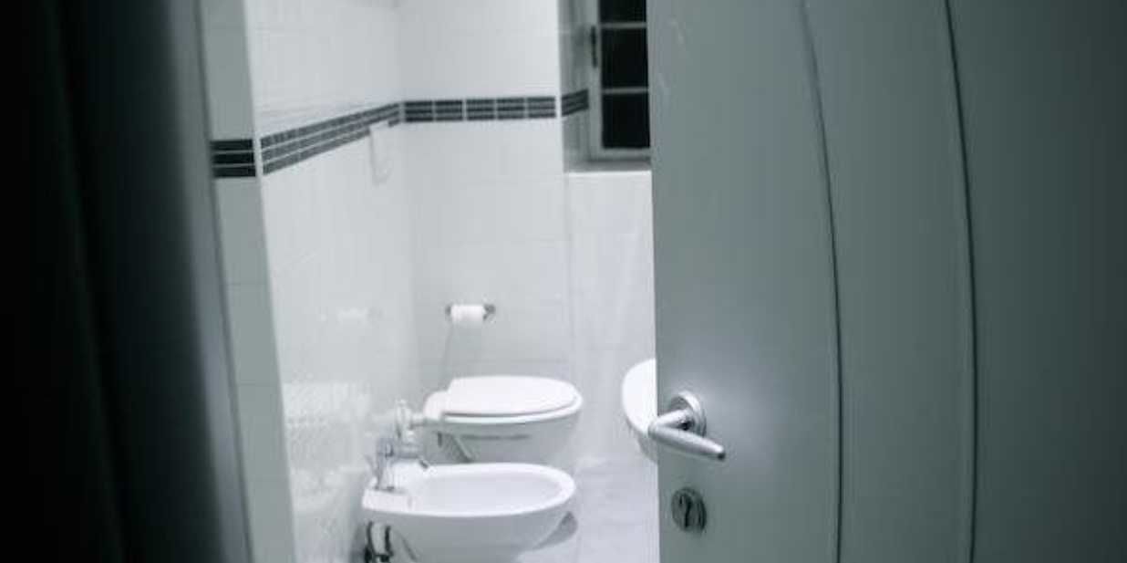 A bathroom with two toilets and a sink.