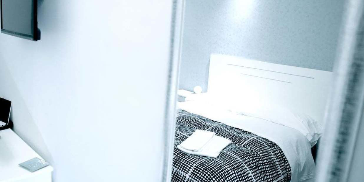 A hotel room with a bed, a nightstand, and a wall-mounted TV.