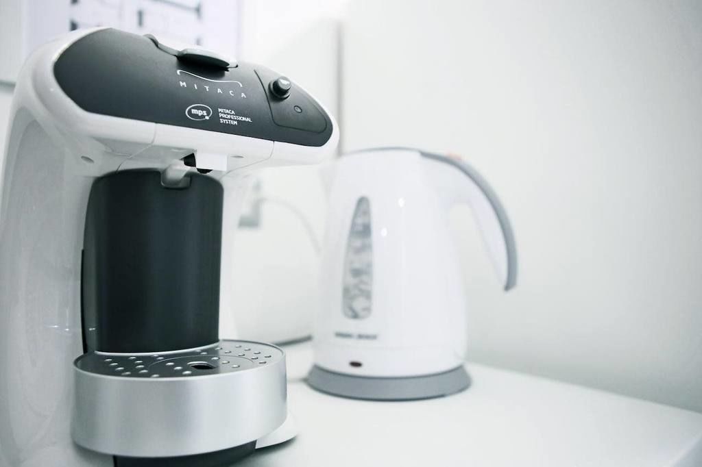 A coffee machine and a kettle on a white countertop.