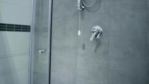 Ducha moderna con cabina de vidrio y ducha empotrada en la pared.