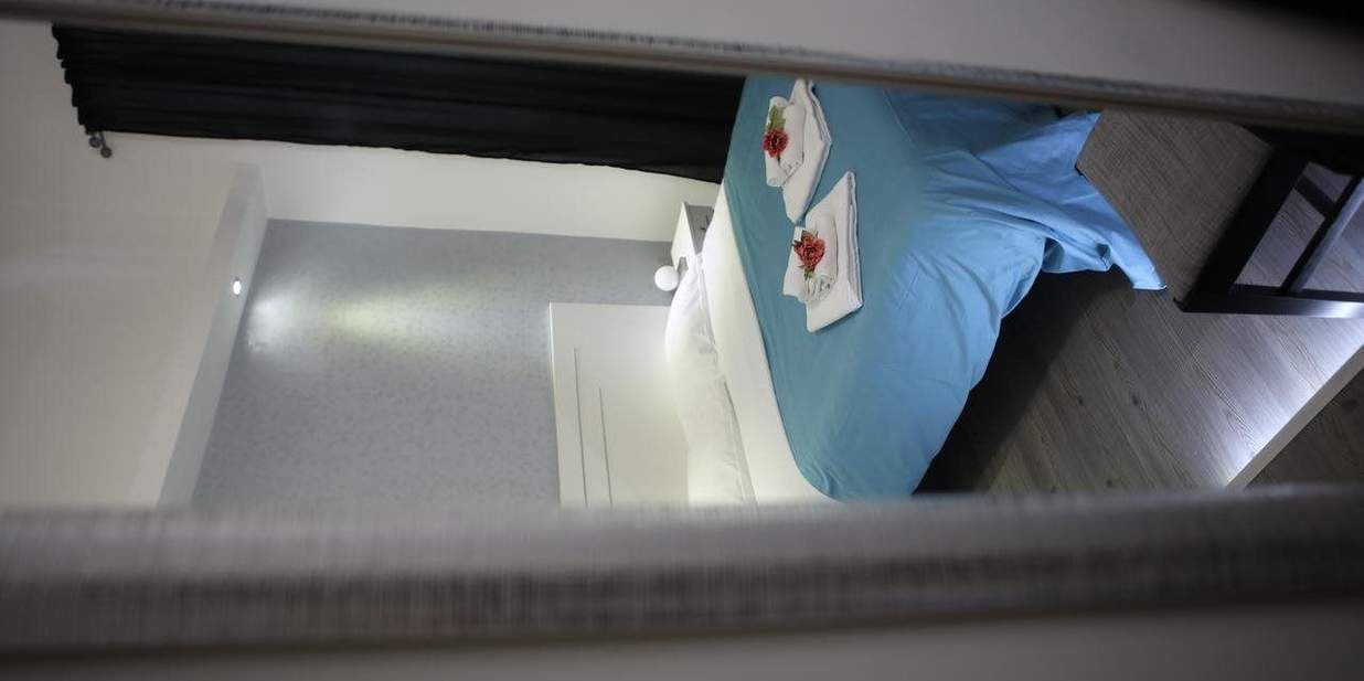 Un dormitorio con colcha azul, almohadas blancas y puerta blanca.