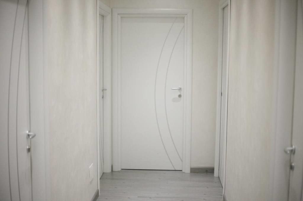 A hallway with a white door, white walls, and a light-colored floor.